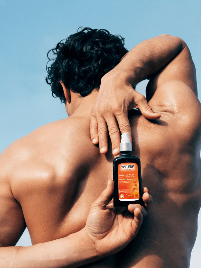 Pessoa-aplicando-o-Oleo-para-Massagem-Weleda-de-Arnica-nas-costas-com-rotulo-laranja-destacando-suas-propriedades-de-recuperacao.